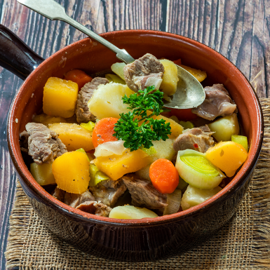 A puréed and simmering carrot soup in a pot with a spoon